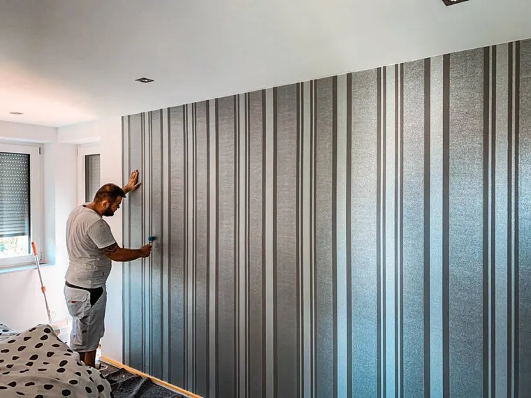 Handwerker bringt sauber eine Mustertapete an der Wand an