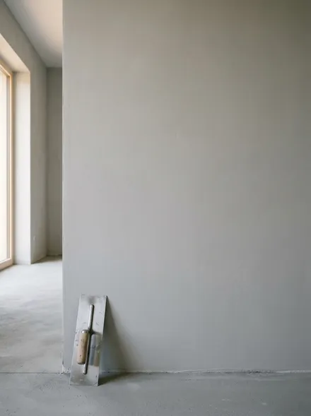 Frisch verputzte, glatt geglättete Innenwand mit Glätter, weiches Fensterlicht zeigt die ebene Fläche