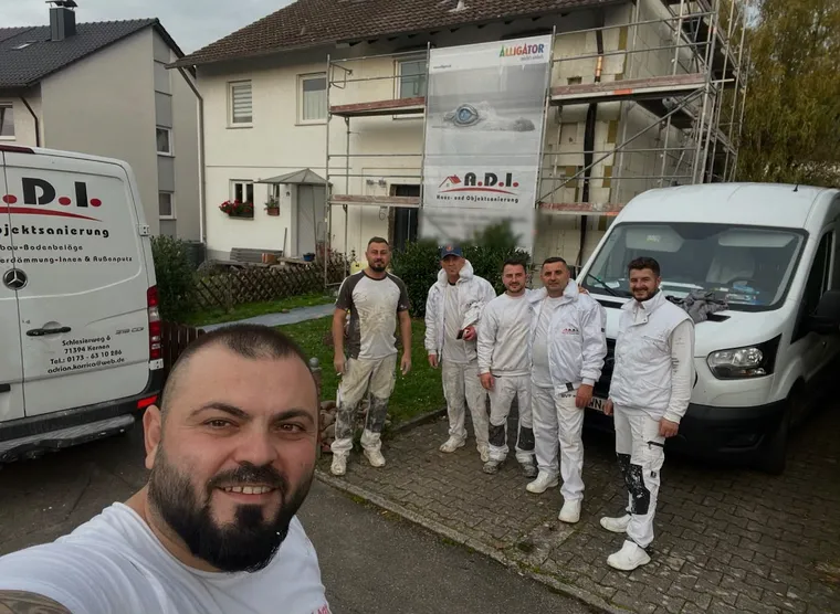 Adrian Karrica und das A.D.I.-Team in Arbeitskleidung vor den Firmenwagen auf einer Baustelle